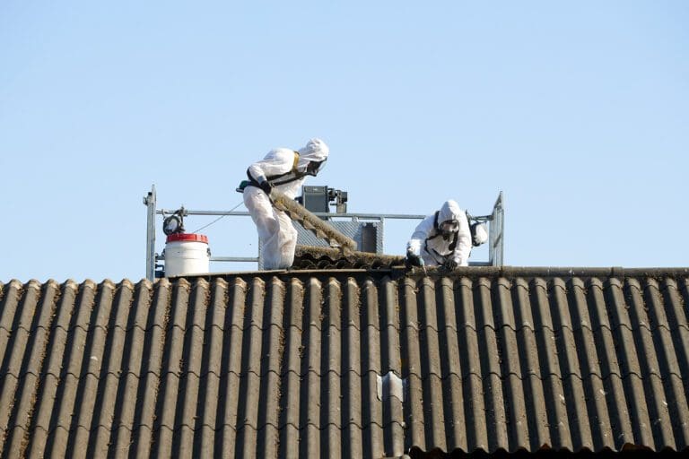 Asbest wordt verwijderd op locatie door medewerkers op het dak